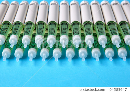 Diabetic insulin pens lined up on a blue background with copy space. Insurance coverage of medicines 94585647