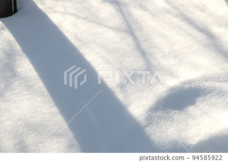 On a sunny winter day, natural shadows from trees form on the snow surface, an abstract pattern On a sunny winter day, natural shadows from trees form on the snow surface, an abstract pattern 94585922