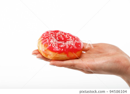 Woman hand holds red donut over white 94586104