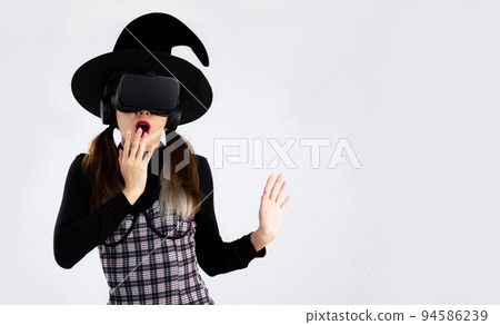 Metaverse concept, halloween theme, young asian girl in witches costume wearing witch hat and vr headset posing watching playing and exciting on white background.. Metaverse concept, halloween theme, young asian girl in witches costume wearing witch hat and vr headset posing watching playing and exciting on white background.. 94586239