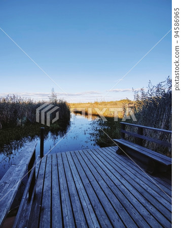 View of a wooden pier on a large crayfish lake. State Natural Reserve Cancer Lakes, St. Petersburg. View of a wooden pier on a large crayfish lake. State Natural Reserve Cancer Lakes, St. Petersburg. 94586965