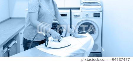ironing white shirt on board in laundry room with washing machine on background ironing white shirt on board in laundry room with washing machine on background 94587477