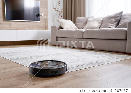 Robotic vacuum cleaner on a floor in cozy modern living room 94587487