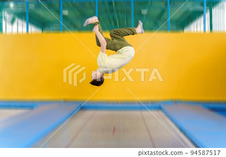 Teenage boy jumping on trampoline park in sport center Teenage boy jumping on trampoline park in sport center 94587517