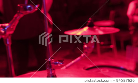 Unrecognizable musician hands hitting drum plates in recording studio. Close up of drummer hands performing solo with drumsticks. Attractive artist playing on drum kit indoor in red light Unrecognizable musician hands hitting drum plates in recording studio. Close up of drummer hands performing solo with drumsticks. Attractive artist playing on drum kit indoor in red light 94587626