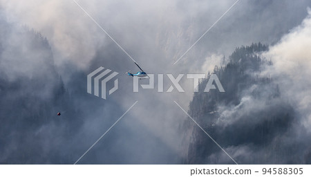 Wildfire Service Helicopter flying over BC Forest Fire and Smoke on the mountain near Hope 94588305