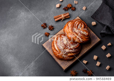 Delicious fresh crispy cinnamon buns sprinkled with coconut crumbs on a wooden cutting board 94588469