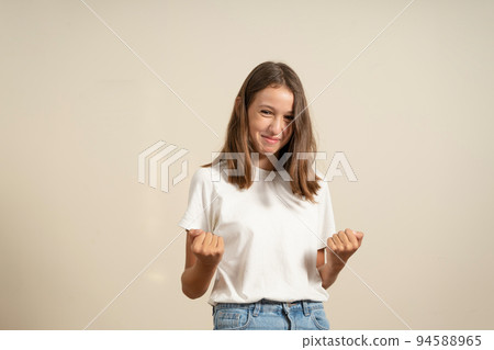 Teenager child girl rejoicing, say yes, looking happy and celebrating victory, champion gesture, fist pump, on beige background Teenager child girl rejoicing, say yes, looking happy and celebrating victory, champion gesture, fist pump, on beige background 94588965