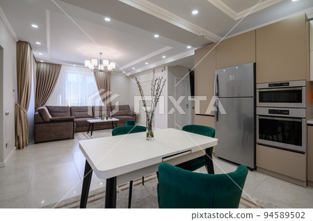 Modern white and beige large luxurious kitchen and dining table in studio apartment 94589502
