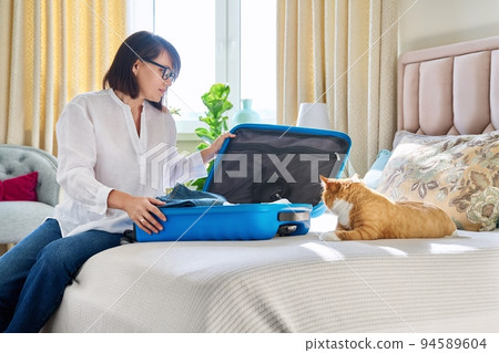 Happy woman packing suitcase with pet cat 94589604