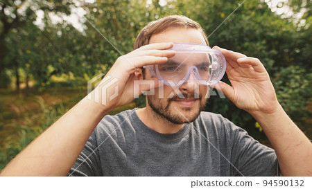 Smiling professionallawn mower wearing transparent glasses protection and and isolating headphones. 94590132