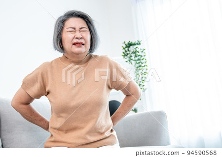 An agonizing senior woman experiencing back pain. 94590568