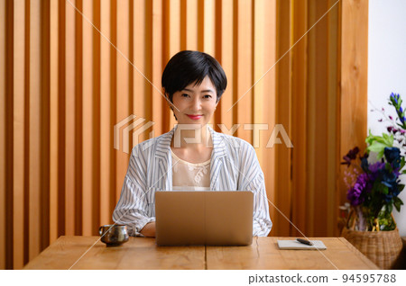 A woman using a computer looking at the camera 94595788