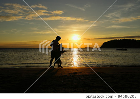 Zushi beach at dusk, silhouette of people playing with dogs Zushi beach at dusk, silhouette of people playing with dogs 94596205