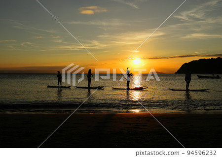 Young people enjoying SUP yoga in the sunlight on the Zushi coast at dusk 94596232