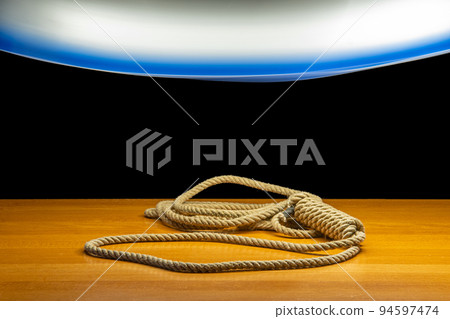 A noose lying on the table under a light of moving chandelier, on a black background A noose lying on the table under a light of moving chandelier, on a black background 94597474