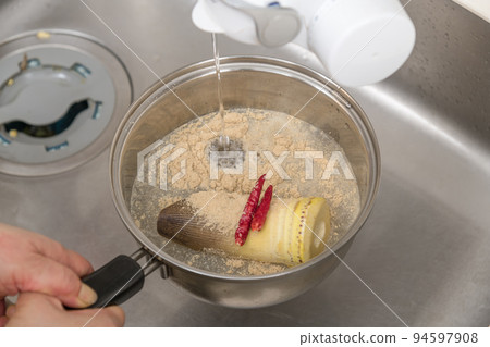 [Pour water into a pot containing ingredients] 94597908