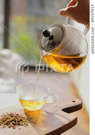Pour delicious freshly brewed herb tea Pour delicious freshly brewed herb tea 94597914