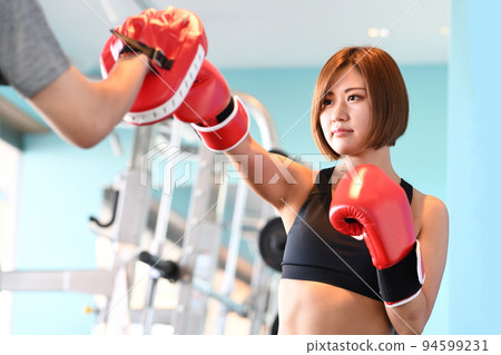 Young woman hitting a mitt in the gym Young woman hitting a mitt in the gym 94599231