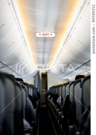 Exit sign in an aircraft interior , Empty seats Inside the airplane 94599352