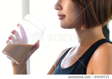 在健身房喝蛋白質的年輕亞洲女性 在健身房喝蛋白質的年輕亞洲女性 94599725