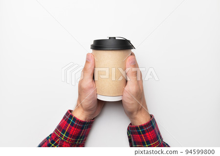 male hands in a plaid shirt hold a paper glass with a hot drink, with a place for an inscription, on a white background. studio shot male hands in a plaid shirt hold a paper glass with a hot drink, with a place for an inscription, on a white background. studio shot 94599800