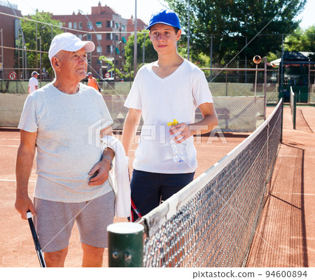 grandfather and grandson talking on court playing tennis grandfather and grandson talking on court playing tennis 94600894