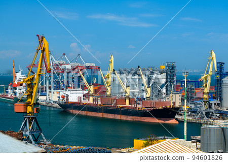 industrial seaport infrastructure, sea, cranes and dry cargo ship, grain silo, bulk carrier vessel and grain storage elevators, concept of maritime cargo transportation 94601826
