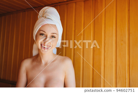 woman topless in a towel on the head sits on a bench in the sauna. woman topless in a towel on the head sits on a bench in the sauna. 94602751