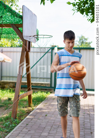 teenage boy playing basketball at home in the backyard, outdoor activities on summer vacation teenage boy playing basketball at home in the backyard, outdoor activities on summer vacation 94603101