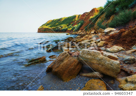 beautiful summer seascape, seashore on a bright day, high hill, wild grass and stones 94603347