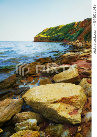 beautiful summer seascape, seashore on a bright day, high hill, wild grass and stones 94603348