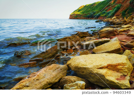 beautiful summer seascape, seashore on a bright day, high hill, wild grass and stones 94603349