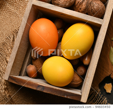 easter holiday still life and decorations, easter eggs in a box with nuts on a dark wooden background 94603450