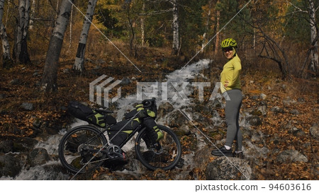 The woman travel on mixed terrain cycle touring with bikepacking. The traveler journey with bicycle bags. Sport tourism bikepacking. The woman travel on mixed terrain cycle touring with bikepacking. The traveler journey with bicycle bags. Sport tourism bikepacking. 94603616
