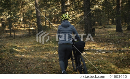 The woman travel on mixed terrain cycle touring with bike bikepacking. The traveler journey with bicycle bags. Magic forest park. The woman travel on mixed terrain cycle touring with bike bikepacking. The traveler journey with bicycle bags. Magic forest park. 94603630