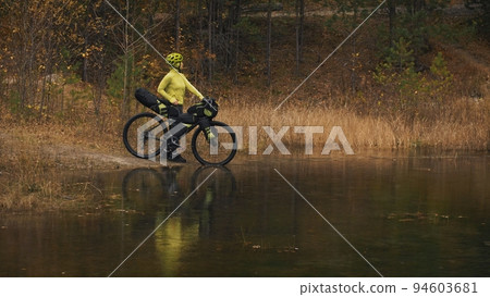 The woman travel on mixed terrain cycle touring with bikepacking. The traveler journey with bicycle bags. Sport tourism bikepacking. 94603681