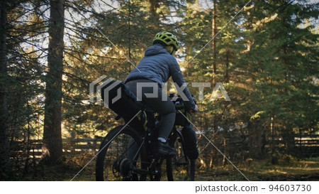The woman travel on mixed terrain cycle touring with bike bikepacking. The traveler journey with bicycle bags. Magic forest park. 94603730