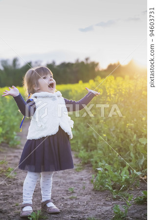 child with Ukrainian ribbons in her hair sings in a flowering field  94603731