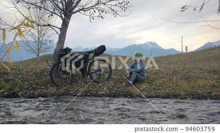 The woman travel on mixed terrain cycle touring with bikepacking. The traveler journey with bicycle bags. Sport tourism bikepacking. The woman travel on mixed terrain cycle touring with bikepacking. The traveler journey with bicycle bags. Sport tourism bikepacking. 94603759