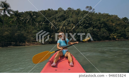 Sportive woman rows pink plastic canoe along sea water. Sportive woman rows pink plastic canoe along sea water. 94603824