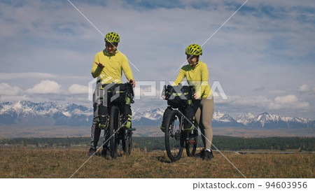 The man and woman travel on mixed terrain cycle touring with bikepacking. The love couple journey with tent in with bicycle bags. Stylish sportswear. 94603956