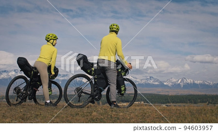 The man and woman travel on mixed terrain cycle touring with bikepacking. The love couple journey with tent in with bicycle bags. Stylish sportswear. 94603957