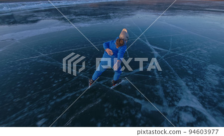 The child train on ice professional speed skating. The girl skates in the winter in sportswear, sport glasses, suit. Outdoor slow motion. 94603977