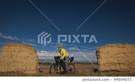 The man travel on mixed terrain cycle touring with bikepacking. The traveler journey with bicycle bags. Sport tourism bikepacking. The man travel on mixed terrain cycle touring with bikepacking. The traveler journey with bicycle bags. Sport tourism bikepacking. 94604055