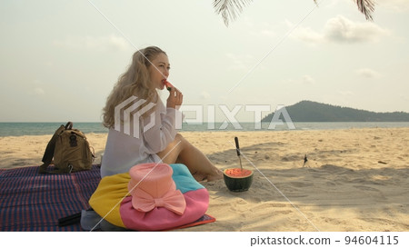 The cheerful woman in holding and eating slices of watermelon on tropical sand beach sea. Portrait attractive girl spend summer weekend. The cheerful woman in holding and eating slices of watermelon on tropical sand beach sea. Portrait attractive girl spend summer weekend. 94604115