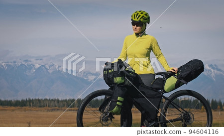 The woman travel on mixed terrain cycle touring with bikepacking. The traveler journey with bicycle bags. Sport tourism bikepacking. The woman travel on mixed terrain cycle touring with bikepacking. The traveler journey with bicycle bags. Sport tourism bikepacking. 94604116