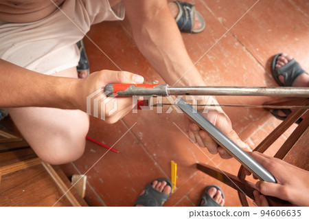 Trimming a wooden plinth with a manual jigsaw. 94606635