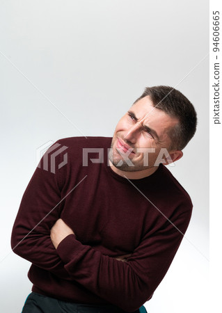 A man touches his stomach with two hands, on a white background with copy space, Stomach pain in a man. 94606665