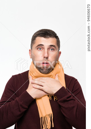A man suffers from a sore throat, a man wrapped his throat with a scarf, portrait on a white background. A man suffers from a sore throat, a man wrapped his throat with a scarf, portrait on a white background. 94606670